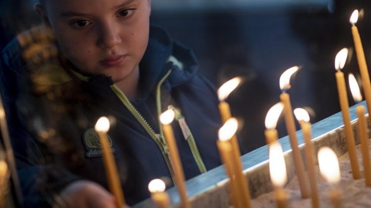 Kind zündet Kerze in einer Kirche an