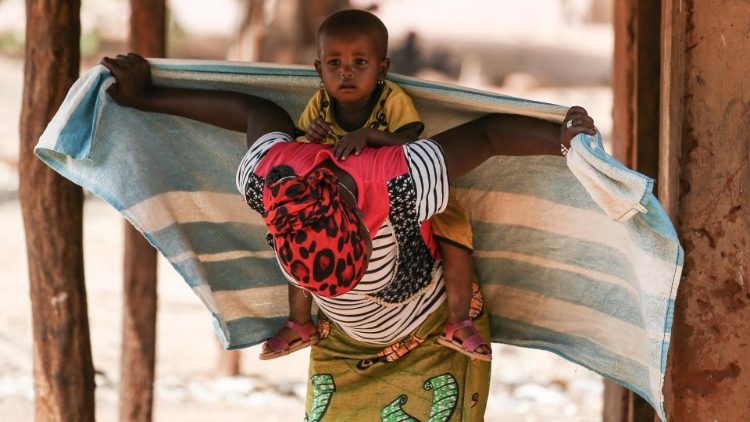 Una donna carica sulle spalle il proprio bambino - Guinea Bissau (EPA)