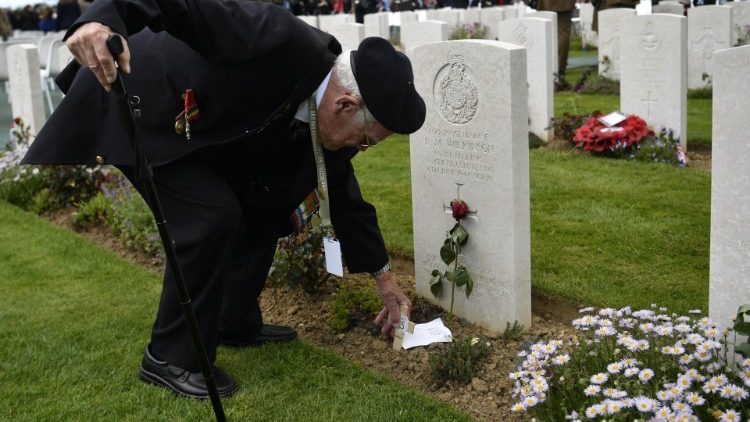 A WWII veteran lays a message at a fallen soldier's grave in Bayeux, France