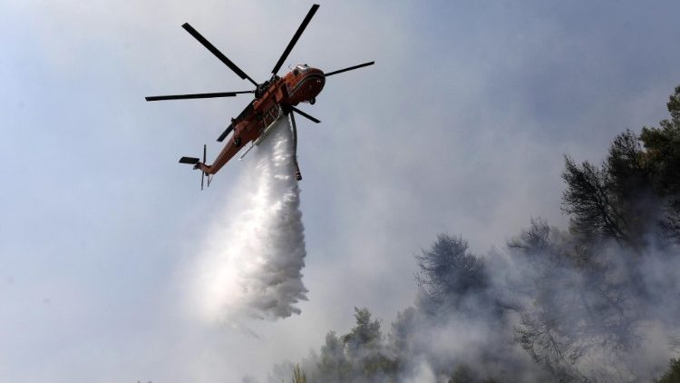 A helicopter drops water over a forest fire on Evia