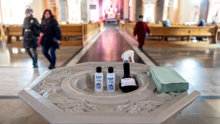 Na Basílica Menor de São Vicente de Paulo em Bydgoszcz, a água benta em tubos plásticos ao lado de desinfetantes para as mãos.