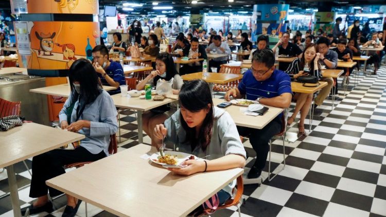 Thailändische Arbeiter essen jeweils an einzelnen Tischen 