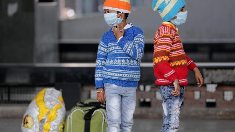 Crianças com máscaras protetoras, em parada de ônibus em Punjab 