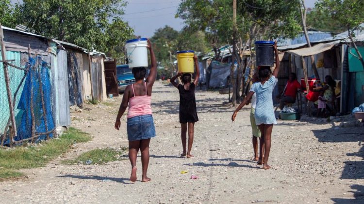 Des Haïtiennes ayant collecté de l'eau au camp de La Piste à Port-au-Prince, le 7 avril 2020
