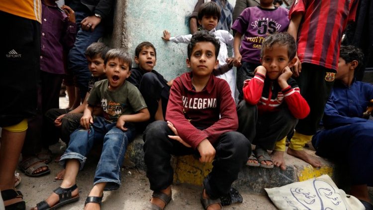 यमन के बच्चे चैरिटी दल से मुफ्त भोजन पाने का इंतजार करते हुए 