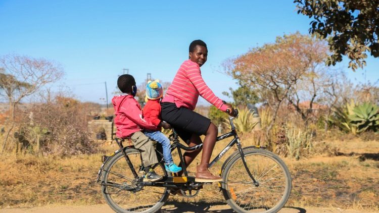 Mãe com seus dois filhos em uma bicicleta em Harare, Zimbabwe 
