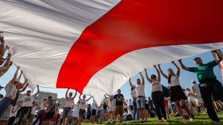 Belarusians hold a giant flag during a protest rally