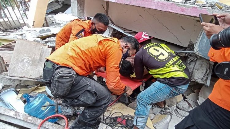 Rescuers pulling a survivor out of the rubble of a collapsed building in West Sulawesi following a 6.2 magnitude earthquake  on 15 January 2021 