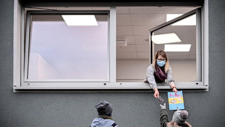 Eine Lehrerin händigt ihren Schülern Lernmaterial durch das Fenster aus - auch die Schulen bleiben während des Lockdowns geschlossen