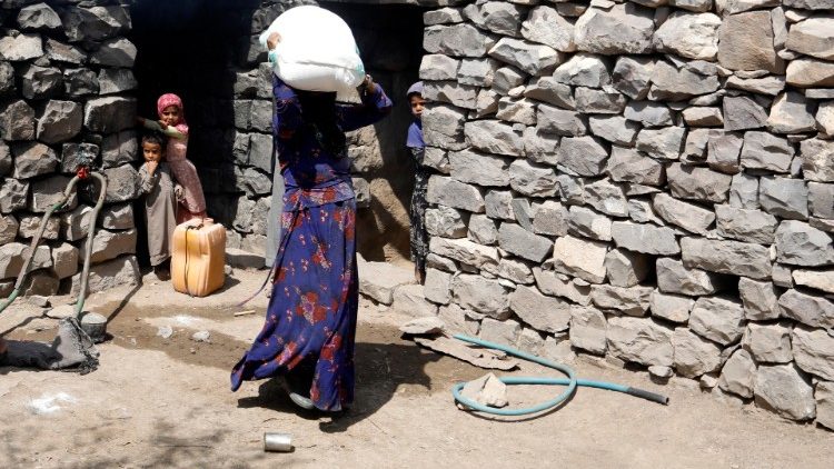 Yemen, in un villaggio di Sana'a una donna trasporta un sacco di farina donatole