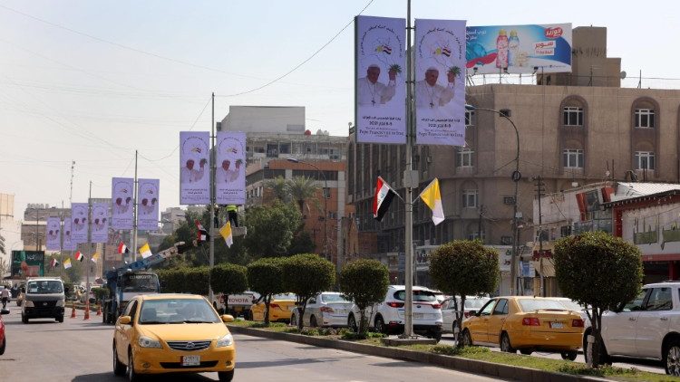 Bagdad sugárútján Ferenc pápa képe és vatikáni zászlók   
