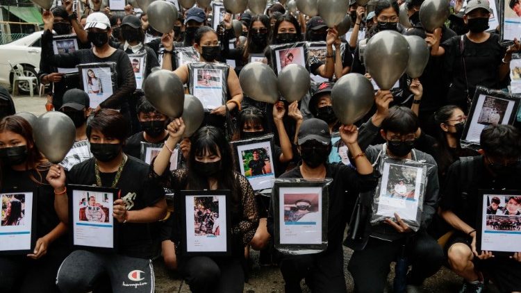 Manifestantes vestidos de negro sostienen fotos de las víctimas que murieron por disparos de las tropas armadas durante una protesta contra el golpe militar en Yangon.