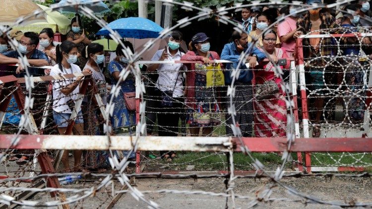 Pessoas esperam atrás de barricadas que seus parentes sejam libertados do lado de fora da entrada principal do complexo prisional de Insein em Yangon, Mianmar.