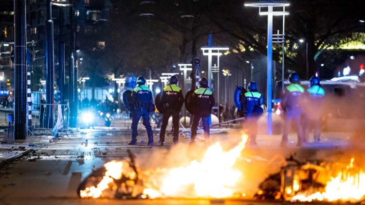 Police in Rotterdam stand near burning objects during protests
