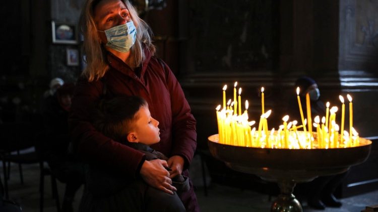 Ucraniana com seu filho chora durante celebração na Catedral dos Santos Pedro e Paulo em Lviv.  EPA/Miguel A. Lopes