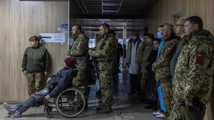 Membros das forças armadas, civis e médicos ucranianos participam de uma dentro de um hospital em Brovary, região de Kiev, Ucrânia, 13 de março de 2022. EPA/PILIPEIA ROMANA