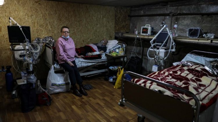 Olena Makukh sits next to her husband Vilaty Makukhis, who has been treated for Covid-19 since 16 February and is now in the underground shelter of Zhytomyr Hospital in Ukraine