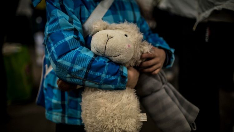 Ein Flüchtlingskind aus der Ukraine umarmt ein Kuscheltier