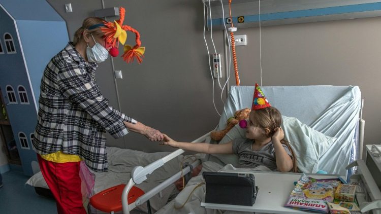 Milana (6), brinca com um palhaço que visita crianças no hospital Ohmatdyt em Kiev, Ucrânia. Milana ficou ferida e sua mãe Diana foi morta em 28 de fevereiro, após bombardeio russo perto de Gostomel. EPA/PILIPEIA ROMANA