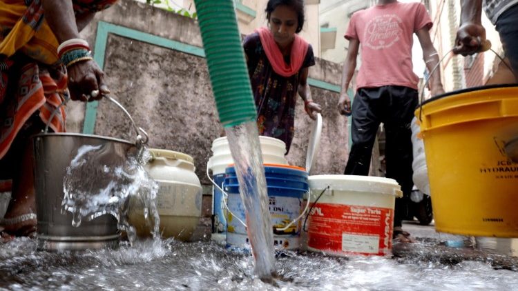 Inder in einem Slum  bei Kalkutta warten auf Kanister mit sauberem Trinkwasser