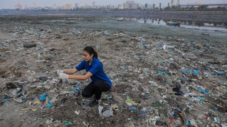 Una volontaria raccoglie i rifiuti di plastica durante la pulizia di una spiaggia a Mumbai, in India, in occasione dell'odierna Giornata della Terra 2022
