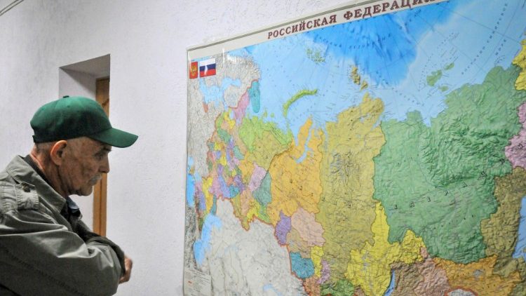 Un uomo guarda una mappa della Federazione russa, in una palestra a Taganrog, nella regione russa di Rostov, in un centro per rifugiati da Mariupol e dall'autoproclamata Repubblica di Donetsk