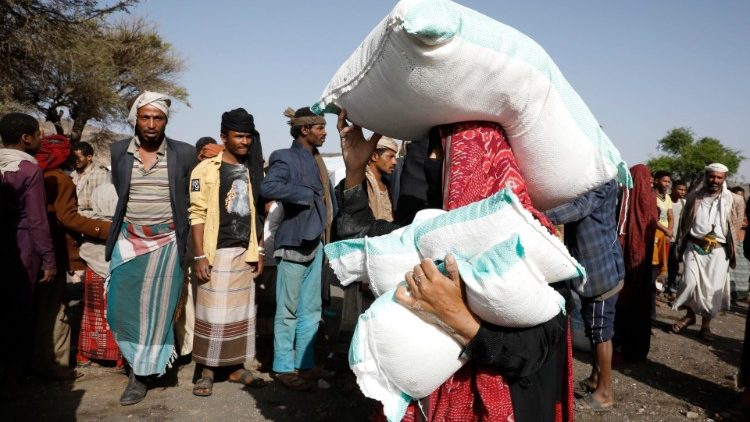 A woman carrying sacks of wheat in war-torn Yemen