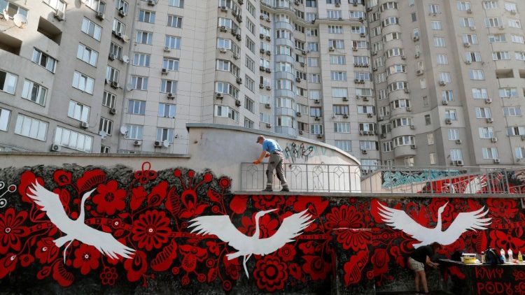 Artistas de rua pintam um mural em uma parede perto de um prédio em uma área residencial em Kyiv, Ucrânia, 18 de agosto de 2022. A artista de rua ucraniana Yulia Abramova, com amigos e colegas, pinta um mural representando um símbolo vermelho da árvore da vida e cegonhas brancas como talismãs , que simbolicamente guardam a Ucrânia durante a invasão russa. As tropas russas entraram em território ucraniano em 24 de fevereiro, iniciando um conflito que provocou destruição e uma crise humanitária. EPA/SERGEY DOLZHENKO