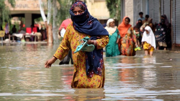 People wade through a flooded area following heavy rains in Dadu District, Farid Abad Sindh province, Pakistan