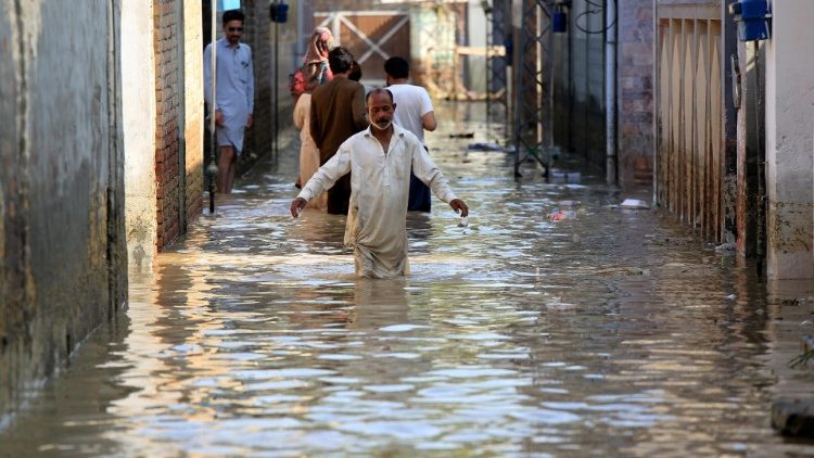 People wade through a flooded arrea in Pakistan  following heavy monsoon rains 