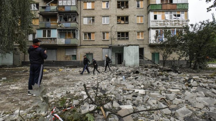 Pessoas caminham entre escombros após bombardeio noturno em Kharkiv, nordeste da Ucrânia, em 21 de setembro de 2022.