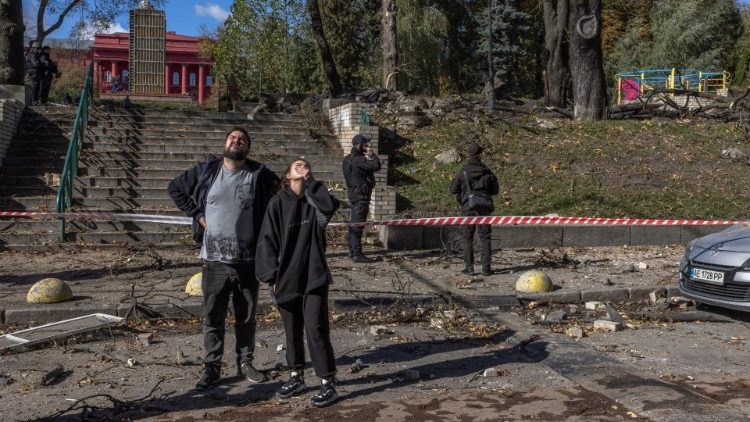 Kiev, una donna e un uomo nei pressi di un parco giochi bombardato