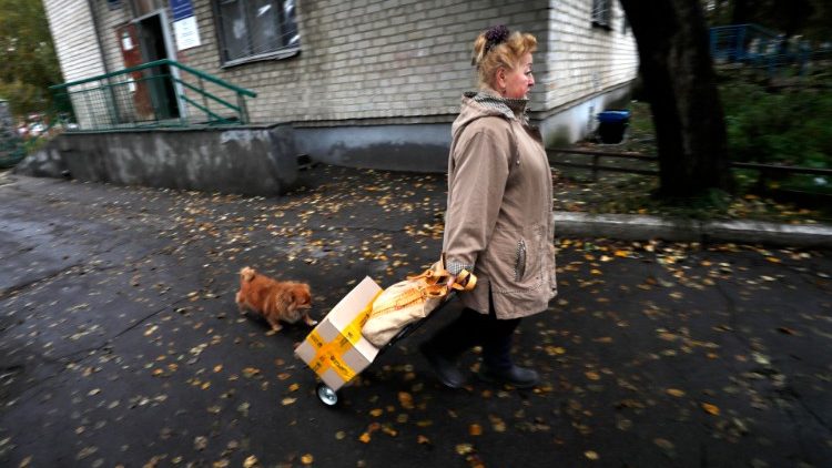 Uma mulher ucraniana carregando ajuda humanitária, na vila de Sviatohirsk, próxima à cidade de Lyman, área de Donetsk, Ucrânia, 11 de outubro de 2022