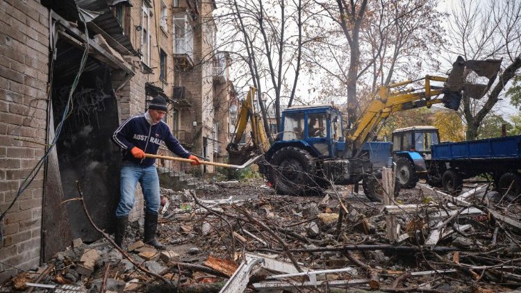 Trabalhadores comunitários limpam destroços de um edifício residencial danificado em um bombardeio noturno na pequena cidade de Druzhkivka, área de Donetsk, Ucrânia, em 26 de outubro de 2022, em meio à invasão russa. EPA/YEVGEN HONCHARENKO