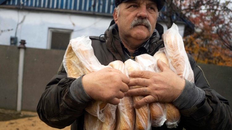 Ucraniano carrega pão distribuído por voluntários na cidade de Kherson, recentemente libertada. EPA/George Ivanchenko