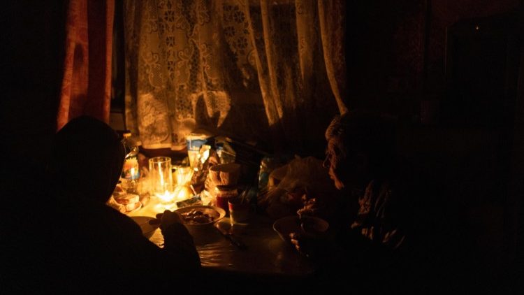 Svitlana i jej dorosły syn Serhiy jedzą kolację przy braku prądu w ich domu w Chersoniu, 25 listopada 2022