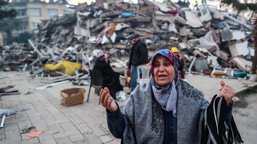 Rea??o de mulher turca enquanto pessoas se aquecem em frente a um prdio desabado aps um grande terremoto em Hatay, Turquia, 08 de fevereiro de 2023.. EPA/ERDEM SAHIN