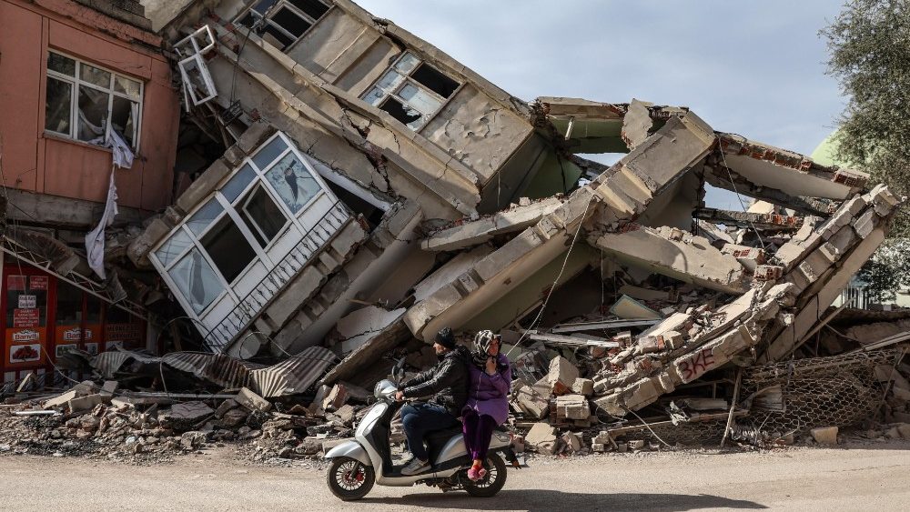 Pessoas passam de moto diante de prdio destrudo em Adiyaman, Turquia, em 19 de fevereiro de 2023. )Photo by EPA/Erdem Sahim)