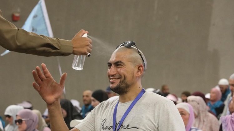 A Saudi soldier sprays water on a pilgrim to cool him off