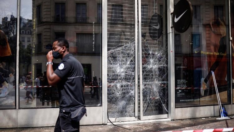 A police officer walks past a broken window caused by riots in Nanterre