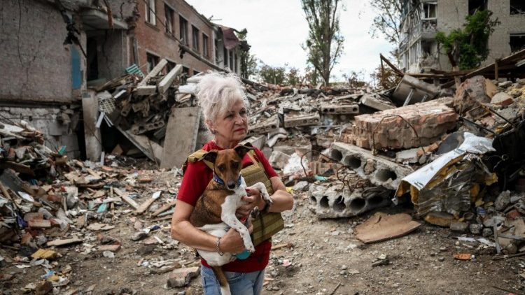 Lubov Jarova segura seu cachorro, Peremoha (vitória), enquanto caminha entre os escombros de uma escola na cidade de Orikhiv, na linha de frente, Oblast de Zaporizhzhia, Ucrânia, 7 de setembro de 2023, em meio à invasão russa. EPA/KATERYNA KLOCHKO