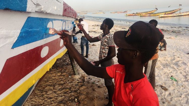 Männer bemalen ein Fischerboot am Strand von Dakar (Senegal)