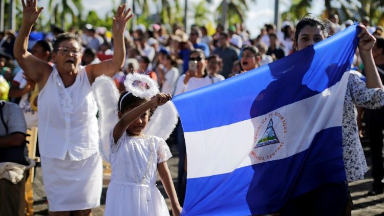 Católicos sostienen bandera nacional durante misa por la paz en Catedral de Managua