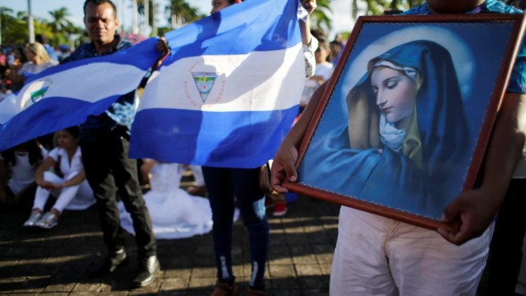 Catholics hold a picture of Virgin Mary and a national flag during a mass for peace in Nicaragua at the Metropolitan Cathedral in Managua