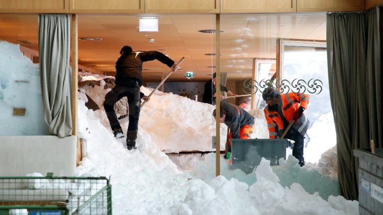 Workers shovel snow out of a restaurant after an avalanche in Switzerland