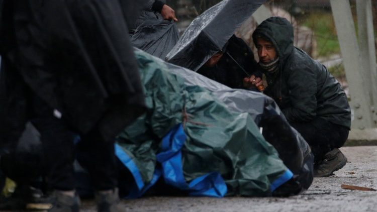 Kurdish migrants from Iran take shelter from the rain, after the dismantling of a camp in Calais