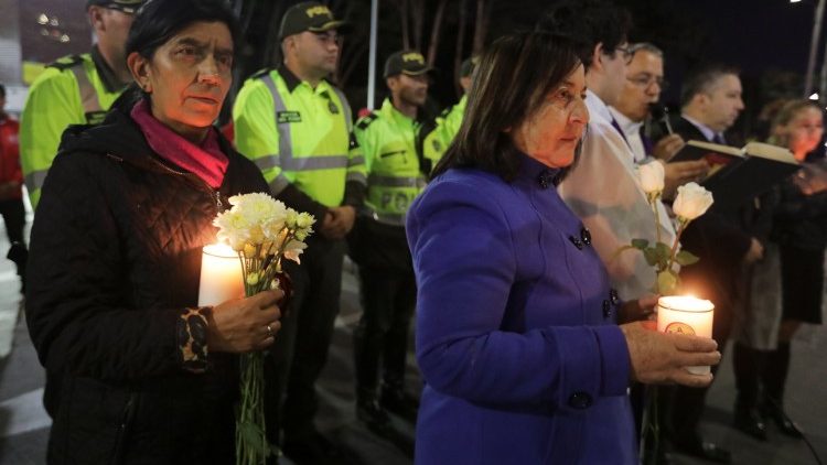 People take part in a candlelight vigil to honor victims, close to the scene of a car bomb explosion, in Bogota