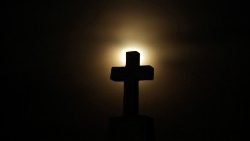 a-cross-headstone-is-silhouetted-against-the--1548037733016.JPG