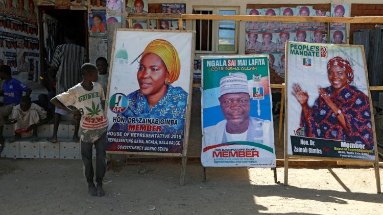 Boys near campaign posters for candidates running for office in the 16 Feb. elections, at the Teachers' Village IDP camp in Maiduguri