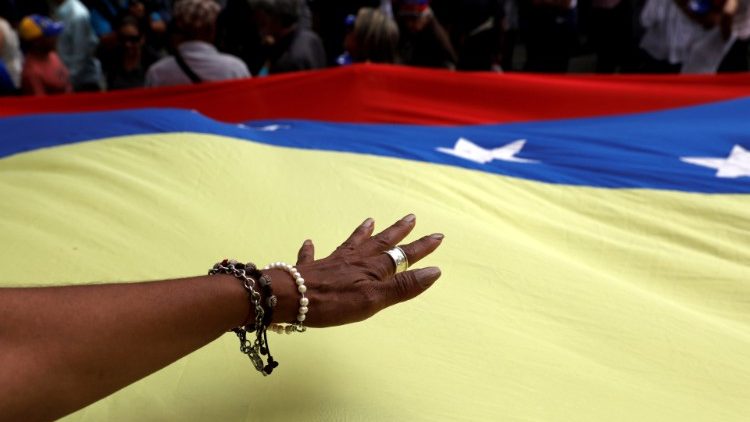 A hand is seen over the national flag during a protest against Venezuelan President Nicolas Maduro's government in Caracas